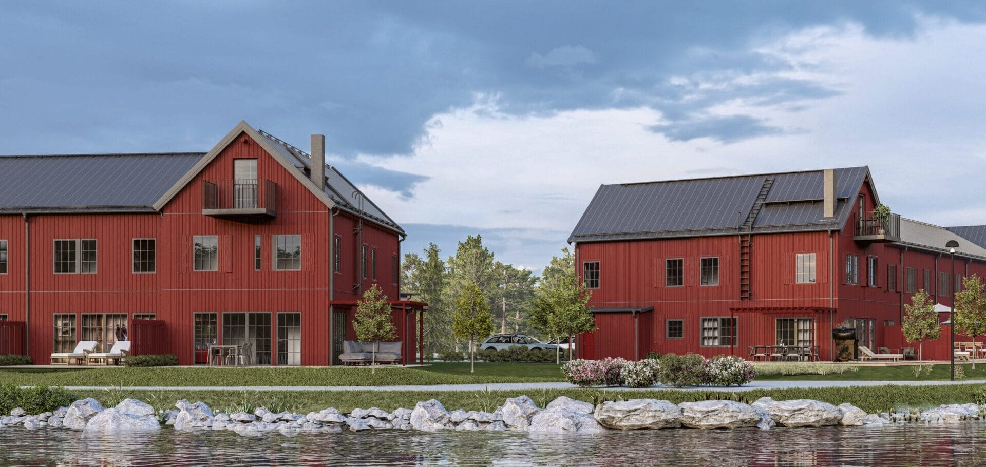 Röda radhuslängor, inspirerade av äldre magasin och båthus, med stora fönster mot vattnet omgivet av grönska.